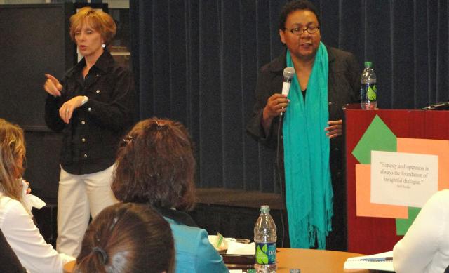 bell hooks standing with microphone and sign language interpretor giving lecture